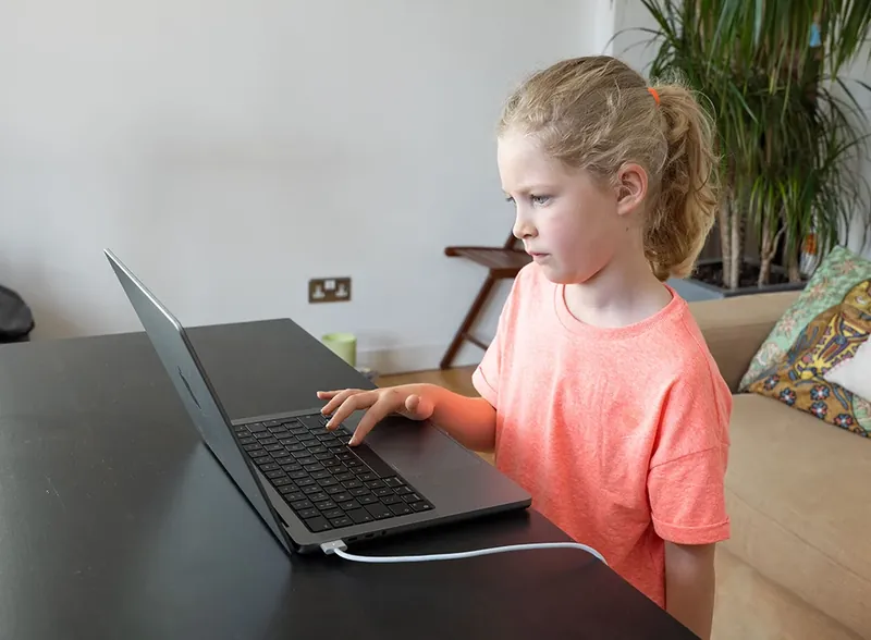 A young girl concentrating on the QbCheck task on a laptop