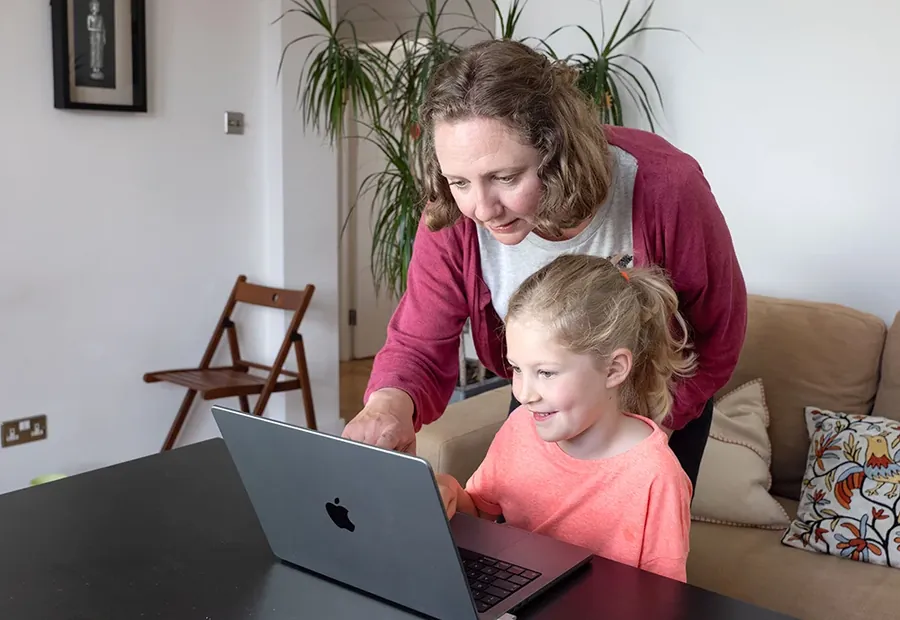A parent helping their child take a QB Check ADHD test on a laptop